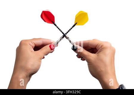 Close-up of two hands holding red and yellow darts crossed on white background, symbolizing competition, challenge, and teamwork. Stock Photo