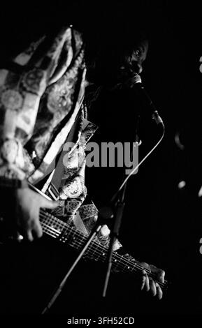 LONDON, UK - FEBRUARY 14, 1994: American avant-garde jazz and free-funk guitarist James Blood Ulmer performing live onstage at Dingwalls nightclub in Camden Lock, London, United Kingdom on February 14, 1994. Ulmer is photographed from a side profile angle, intensely singing into a stage microphone while playing his electric guitar. Dressed in a highly detailed, patterned silk coat, highlighted starkly under deep, high contrast low key concert lighting. This archival monochrome music photograph records a powerful Valentine's Day showcase during his touring era Stock Photo