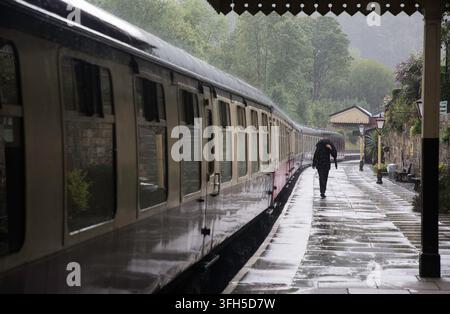 Station guard in the rain at Llangollen railway station Stock Photo