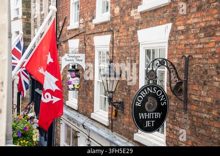 Yorkshire, UK – 24 July 2025: Shop signs and flags displayed on Sandgate, Whitby Stock Photo
