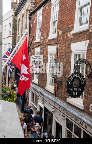 Yorkshire, UK – 24 July 2025: Shop signs and flags displayed on Sandgate, Whitby Stock Photo