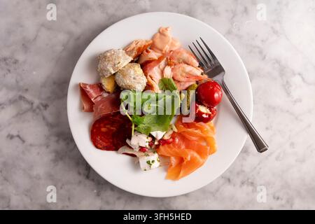 Delicious Assortment of Cured Meats and Fresh Ingredients on a White Plate Stock Photo