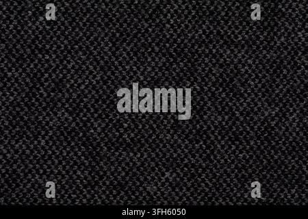 Macro texture of dark charcoal grey knitted wool fabric with tight woven pattern. Fine knitwear background with subtle light highlights Stock Photo