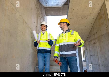 Female and male engineers discussing project while walking downstairs Stock Photo