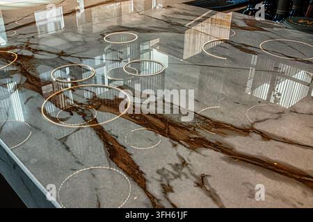 An integrated invisible induction cooktop embedded beneath a polished marble or quartzite countertop Stock Photo
