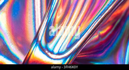 Abstract close-up of glossy holographic metal surface with flowing iridescent rainbow reflections, vibrant spectral colors, curved lines, and futurist Stock Photo