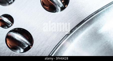 Abstract close-up of reflective water droplets on a brushed metallic surface beside a curved chrome edge, creating a sleek futuristic technology backg Stock Photo
