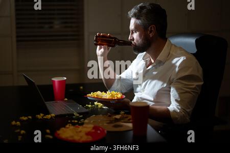 Senior Business man eat pizza overtime. Busy man eating dinner and working online at night office. Entrepreneur works late at night while enjoying a Stock Photo