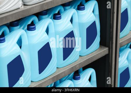 Blue plastic containers of cleaning liquid arranged on storage shelf. Household cleaning background for detergent hygiene supplies and sanitation. Stock Photo