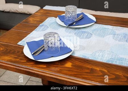 Dining table set with plates glasses and cutlery for two people. Home dining background for meal preparation table setting dinner and hospitality. Stock Photo