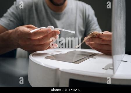Cropped shot of technician comparing worn and new spinning brushes on robot vacuum cleaner. Concept of importance of regular maintenance and Stock Photo