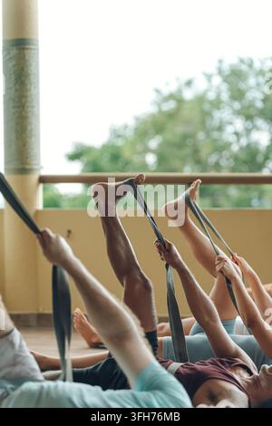 Diverse group of people performing stretching exercises with yoga straps during a fitness class Stock Photo