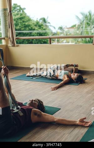 People practicing yoga with an instructor in an outdoor studio Stock Photo