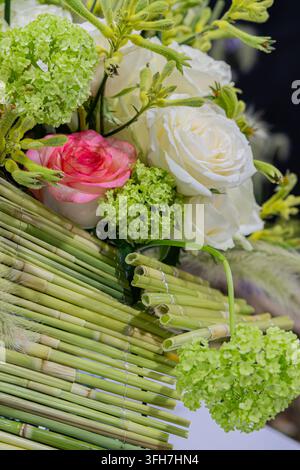 Floral arrangement featuring white and pink roses, green hydrangeas, bamboo sticks, soft even lighting, blurred background, indoor setting, profession Stock Photo