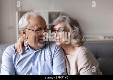 Happy senior couple sitting together on sofa at home Stock Photo