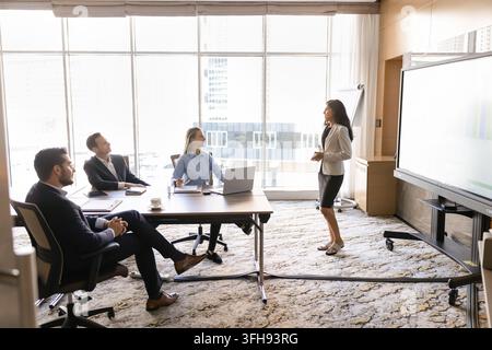 Businesswoman speaking to clients or team members in conference room Stock Photo