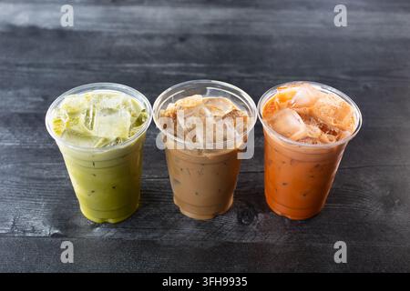 A view of a set of three ice cold drinks in plastic cups, green Thai tea, Vietnamese coffee, and Thai tea. Stock Photo