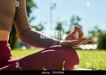Woman Practicing Mindfulness Meditation on Lawn in Park Stock Photo