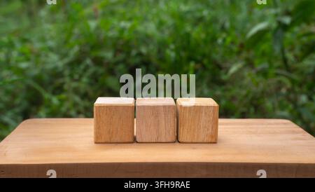 Three Wooden Cubes on Rustic Table with Green Nature Background Stock Photo
