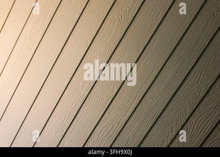 A wooden siding panel with diagonal lines and embossed grain texture, creating neutral architectural background with warm natural detail and repeating Stock Photo