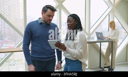 Diverse colleagues discussing a project on a digital tablet Stock Photo