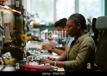 Black Woman Engineer Using Laptop in Electronics Laboratory Stock Photo