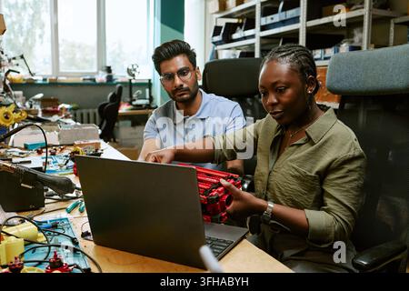 Multiethnic Engineers Developing Robotics Using Laptop in Workshop Stock Photo