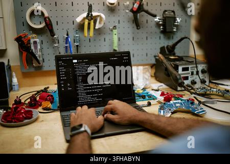Man Programming Hardware and Coding on Laptop in Workshop Stock Photo