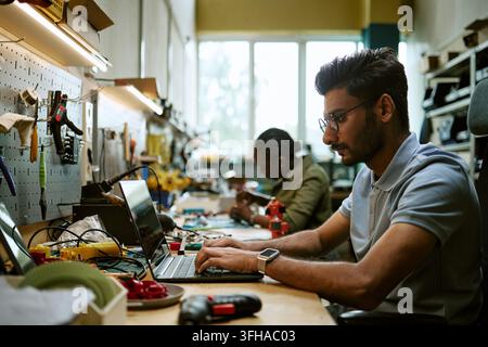 Indian Engineer Coding on Laptop in Hardware Workshop Stock Photo