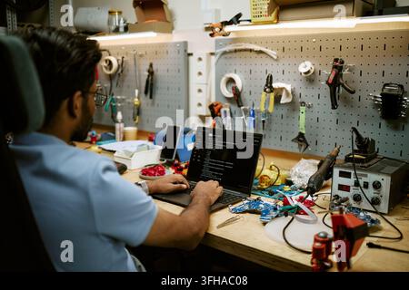 Indian Electronics Engineer Coding on Laptop in Hardware Workshop Stock Photo
