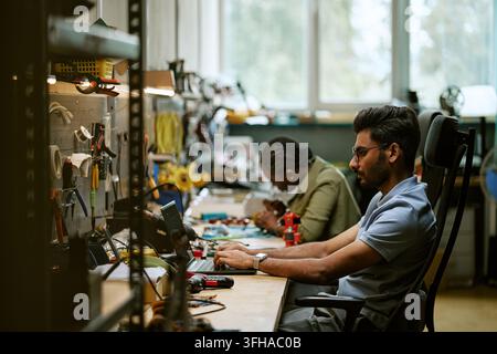 Indian Man Working on Laptop in Electronics Workshop Stock Photo