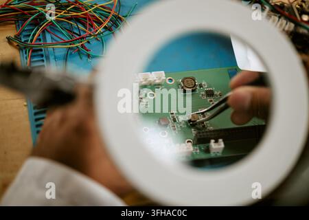 Engineer Repairing Electronic Circuit Board with Tweezers Stock Photo