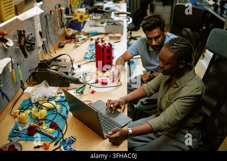 Diverse Engineers Developing Hardware Components on Laptop in Workshop Stock Photo