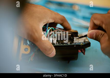 Hands of Man Repairing Electronic Circuit Board with Tool Stock Photo
