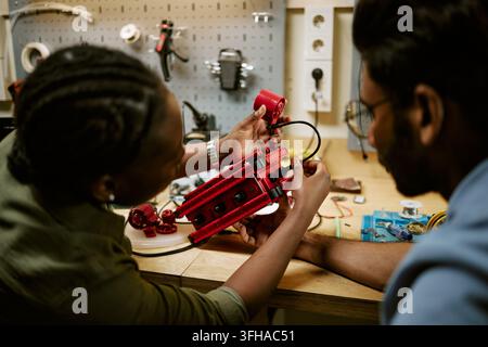 Diverse Engineers Assembling Robotic Prototype in Workshop Stock Photo