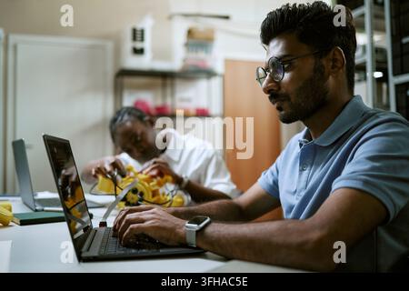 Indian Man Coding on Laptop during Robotics Engineering Workshop Stock Photo