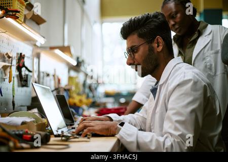 Diverse Engineers Working on Laptop in Robotics Laboratory Stock Photo