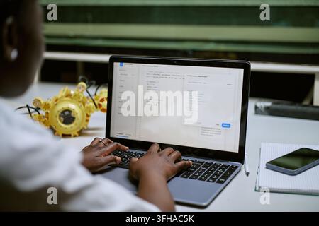 Black Woman Coding Software on Laptop for Robotics Project Stock Photo