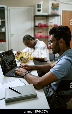 Indian Man Coding on Laptop in Robotics Technology Laboratory Stock Photo