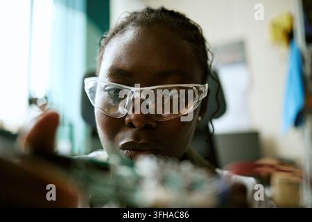 Black Woman Engineer in Safety Glasses Inspecting Circuit Board Stock Photo