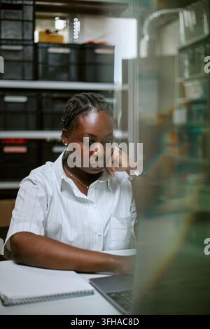 Focused Black Woman Working on Laptop in Modern Office Stock Photo