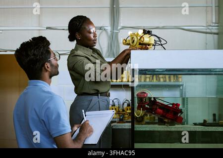 Black Woman Engineer Testing Underwater Robotics with Colleague Stock Photo