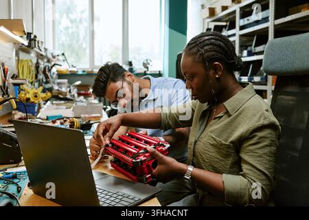 Multiethnic Engineers Assembling Robotic Prototype in Lab Stock Photo