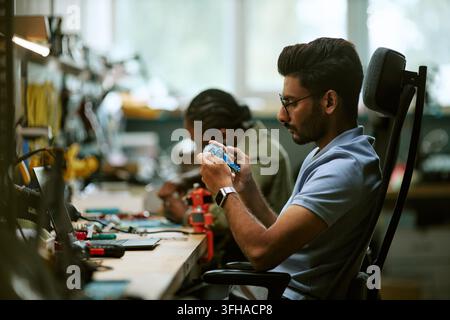 Indian Engineer Inspecting Circuit Board in Hardware Workshop Stock Photo