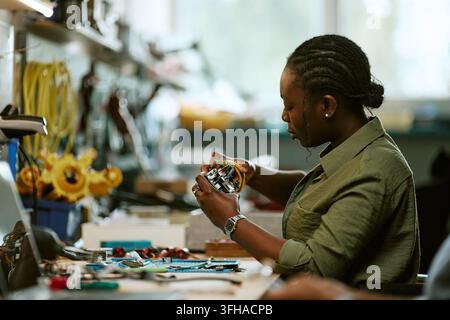 Black Woman Engineer Assembling Circuit Board in Workshop Stock Photo