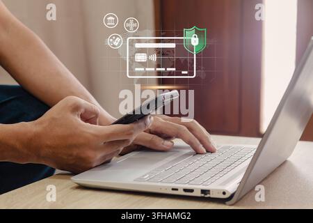 A person using a smartphone and laptop to manage finance safely with advanced security protection features. Secure online banking and digital payment Stock Photo