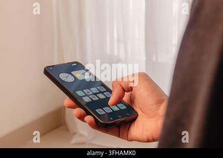 A person holding a smartphone displaying a home screen with multiple application icons and widgets. Scrolling through apps. Stock Photo