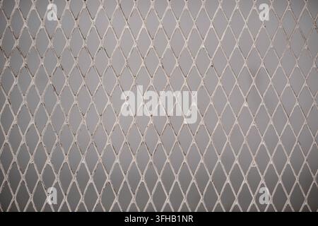 Full frame background texture of a light grey diamond-shaped expanded metal wire mesh screen. Stock Photo