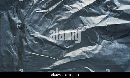 Black shiny crumpled plastic texture background abstract wrinkled film surface copy space Stock Photo