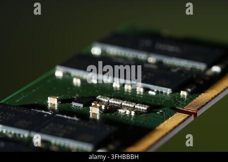 Close-up of a computer RAM memory module with a green circuit board and gold contacts. Stock Photo